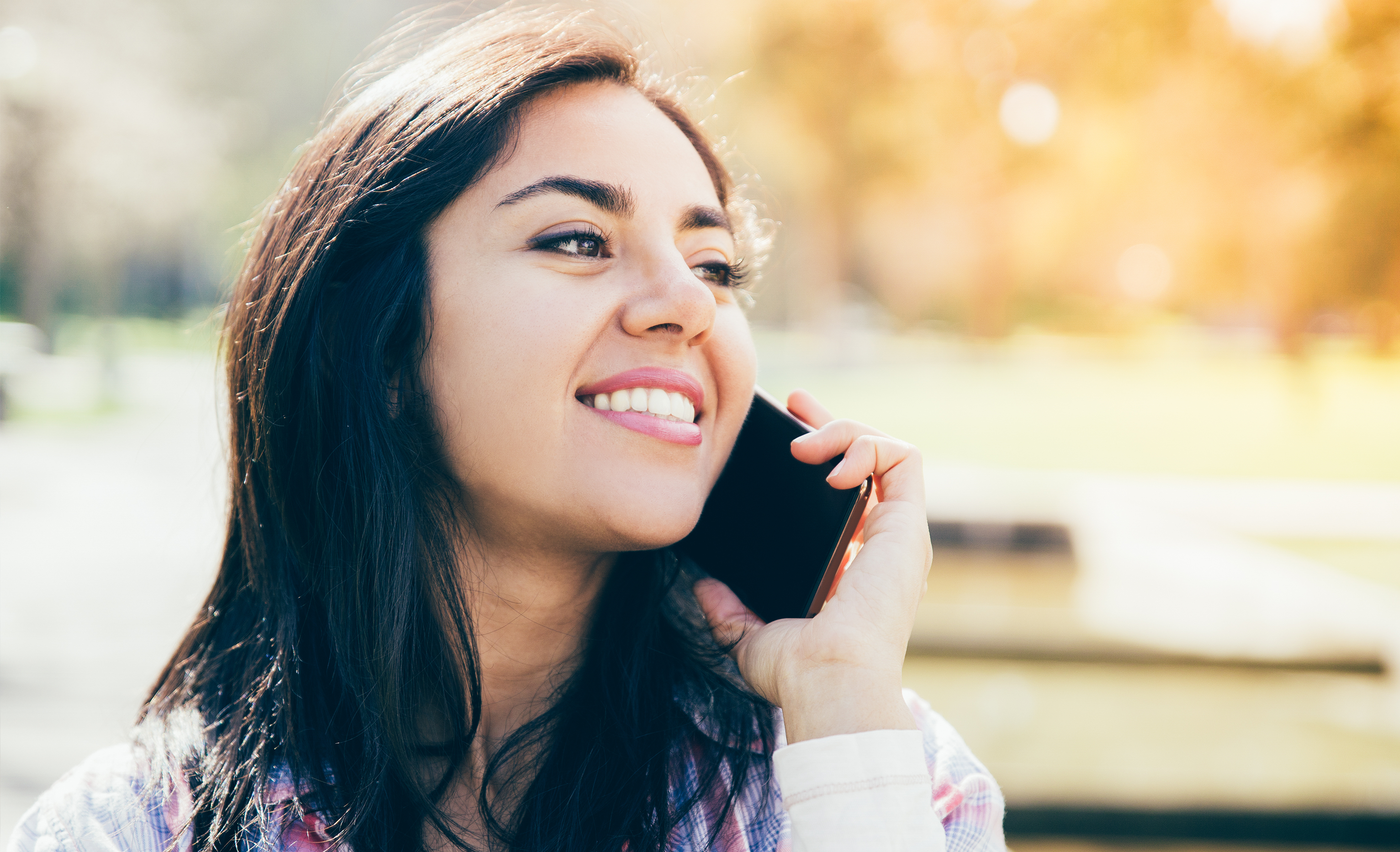A young woman sitting in a park talking on her cell phone